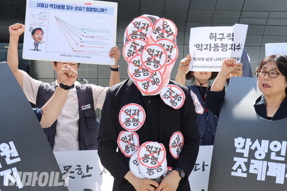 오세훈 서울시장 가면을 쓴 활동가의 얼굴과 몸에 “억지 동행”이라고 쓰인 스티커가 잔뜩 붙어 있다. 사진 김소영