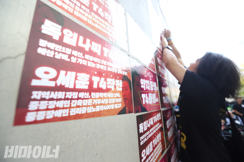 한 활동가가 “독일 나치 T4작전, 오세훈 T4작전”이라고 적힌 스티커를 벽면에 붙이고 있다. 사진 강혜민