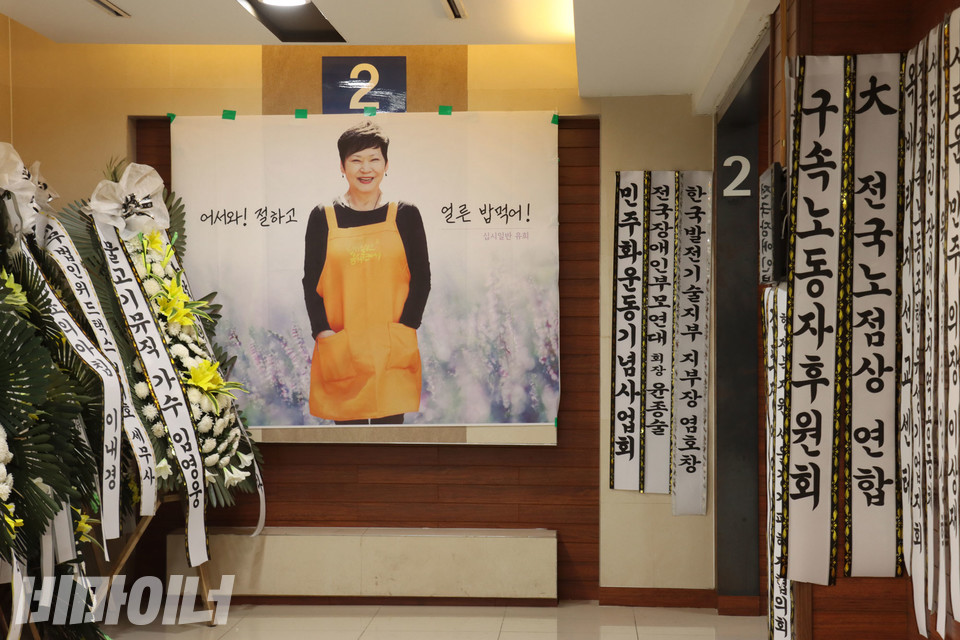 “어서 와. 절하고 얼른 밥 먹어!” 빈소로 들어가는 벽면 왼쪽에는 밥묵차를 상징하는 주황색 앞치마를 입고 환히 웃는 유희의 모습이 조문객을 맞이하고 있다. 그 양옆으로는 시민사회단체 이름이 적힌 하얀 리본이 벽면에 빼곡히 걸려 있다. 사진 강혜민 