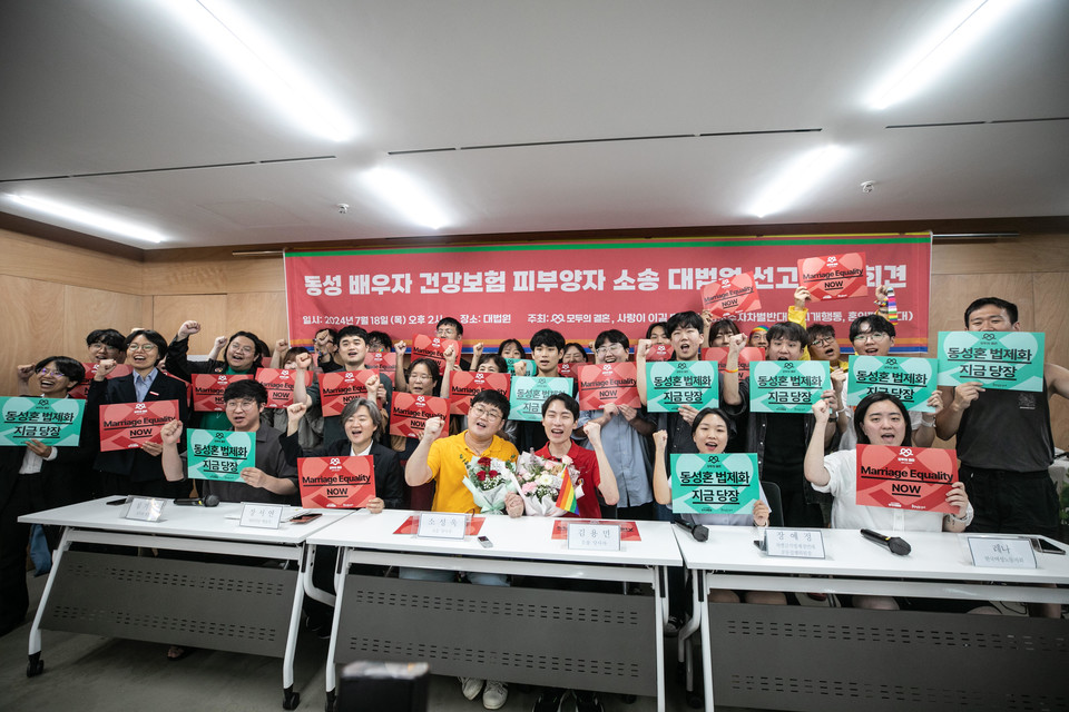 18일, 대법원의 동성 배우자의 건강보험 피부양자 지위 인정 판결 이후 기자회견이 진행됐다. 소성욱 씨와 김용민 씨를 포함한 기자회견 참여자들이 주먹을 불끈 쥐고 있다. 사진 모두의 결혼 제공