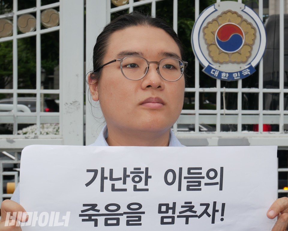 한 활동가가 “가난한 이들의 죽음을 멈추자!”라는 피켓을 들고 있다. 사진 하민지