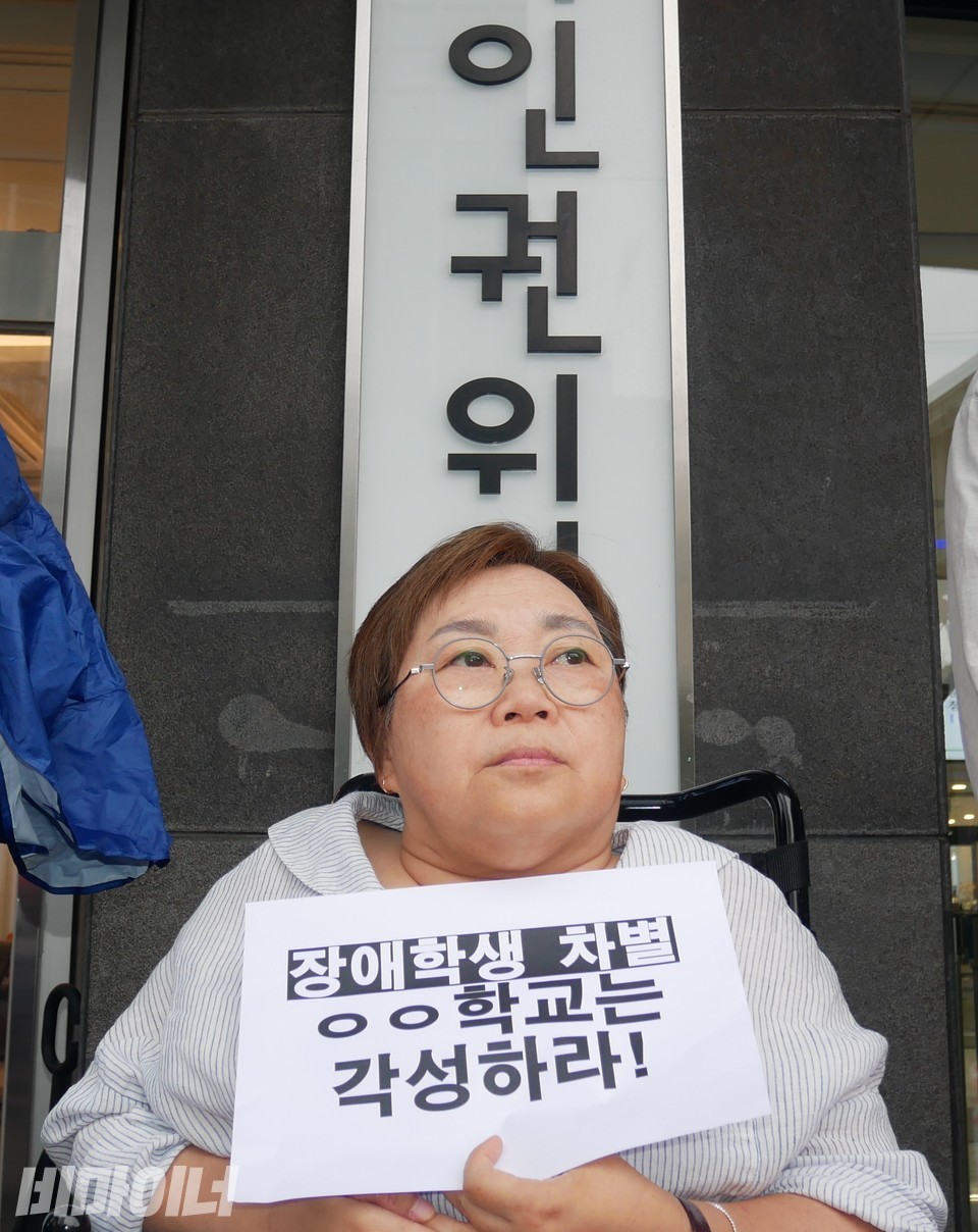 박김영희 장애인차별금지추진연대 대표가 “장애학생 차별하는 늘푸른고등학교는 각성하라”라고 적힌 피켓을 들고 있다. 사진 하민지