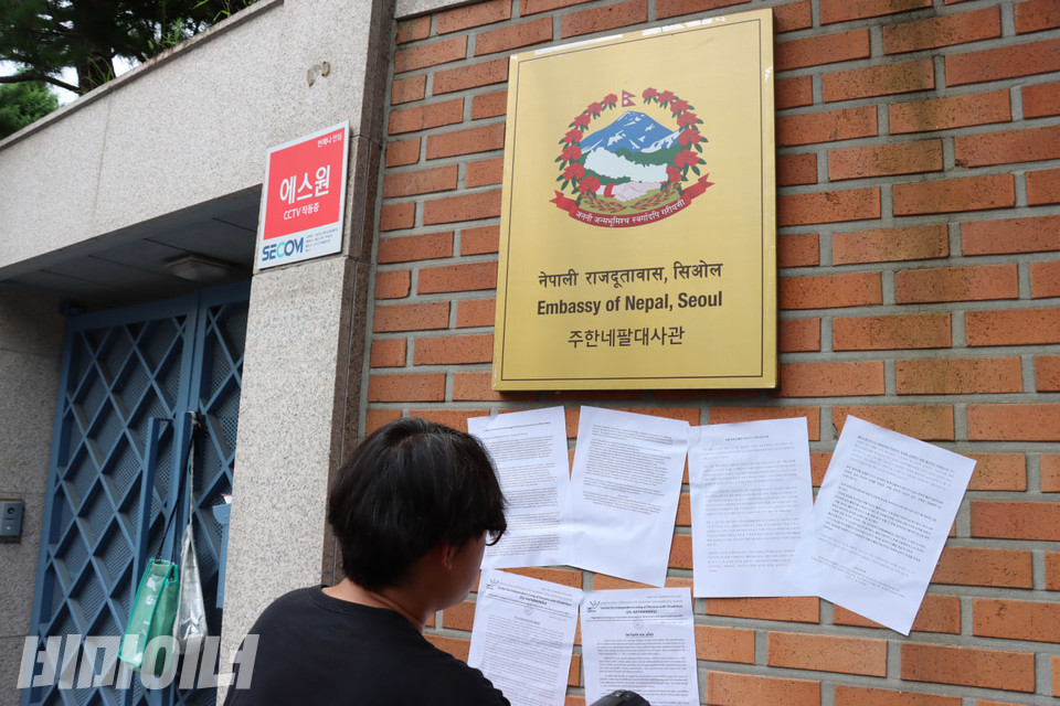 기자회견 참가자들이 ‘네팔 장애인 활동지원서비스 투쟁 연대 서한’을 주한 네팔대사관 벽에 붙이고 있다. 사진 김소영
