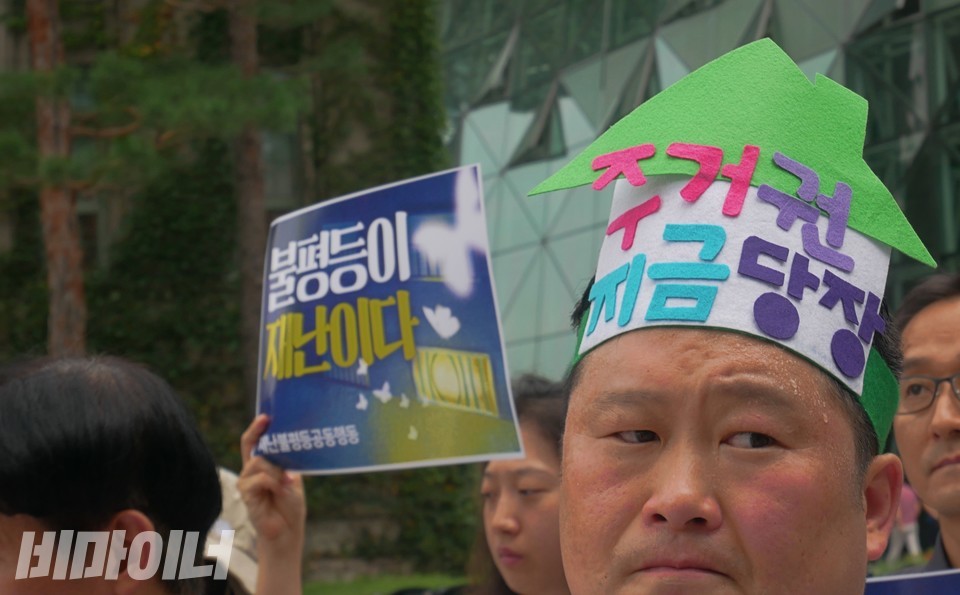 한 기자회견 참가자가 머리에 “주거권 지금 당장”이라 적힌 장식을 했다. 이마에 땀이 맺혀 있다. 사진 하민지