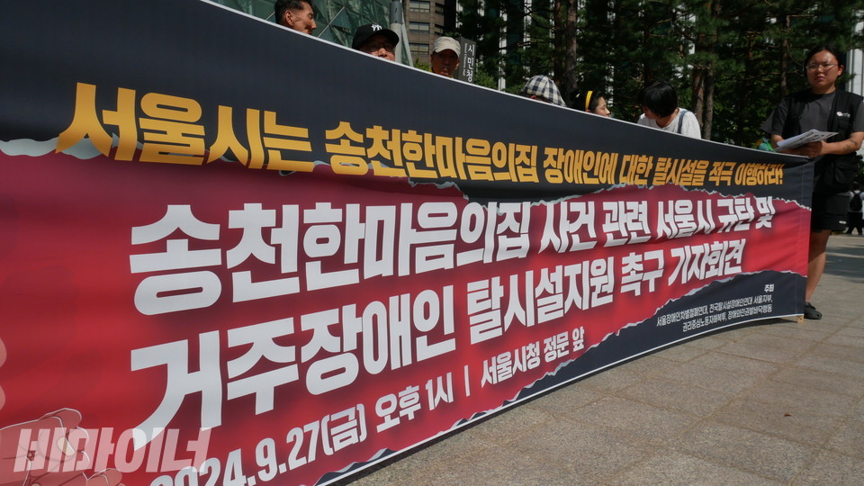 기자회견 현수막에 “서울시는 송천한마음의집 장애인에 대한 탈시설을 적극 이행하라! 송천한마음의집 사건 관련 서울시 규탄 및 거주장애인 탈시설지원 촉구 기자회견”이라 적혀 있다. 사진 하민지