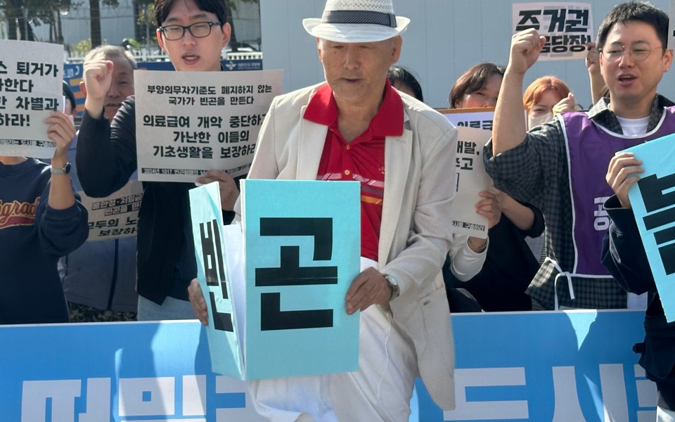 김호태 동자동사랑방 전 대표가 “빈곤”이라고 적힌 손팻말을 부수는 퍼포먼스를 보여주고 있다. 사진 1017 빈곤철폐의 날 조직위원회