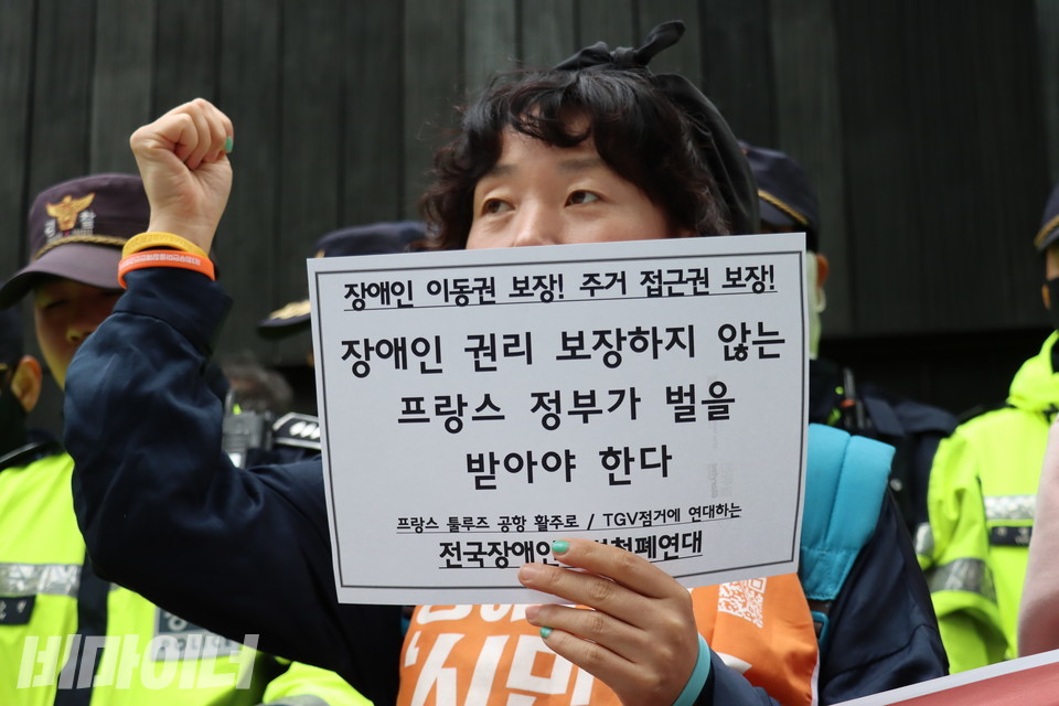 전장연 활동가가 “장애인 권리 보장하지 않는 프랑스 정부가 벌을 받아야 한다”고 적힌 종이 피켓을 들고 있다. 사진 김소영