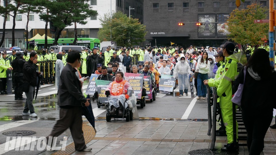 지나가는 시민이 행진하는 장애인운동 활동가들을 쳐다보고 있다. 사진 하민지