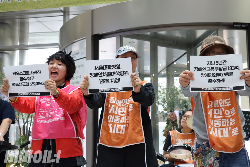 기자회견 참가자들이 종이 피켓을 들며 구호를 외치고 있다. 종이 피켓에는 “키오스크로 사라진 접수 창구 의료접근권 보장하라!”, “서울대학병원, 장애인차별대학병원 1호점 지정!”, “지난 5년간 장애인고용부담금 133억! 장애인의무고용률 준수하라!”라고 적혀있다. 사진 김소영