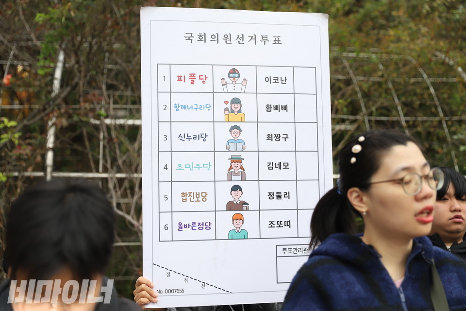 기자회견 참가자가 그림 투표용지의 예시가 그려져 있는 피켓을 들고 있다. 사진 김소영