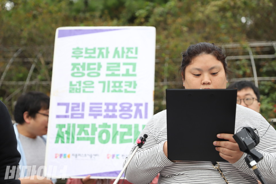  박경인 피플퍼스트서울센터 활동가가 발언하고 있다. 박 활동가의 뒤로는 “후보자 사진, 정당 로고, 넓은 기표칸 그림 투표용지 제작하라!”라고 적힌 피켓이 보인다. 사진 김소영