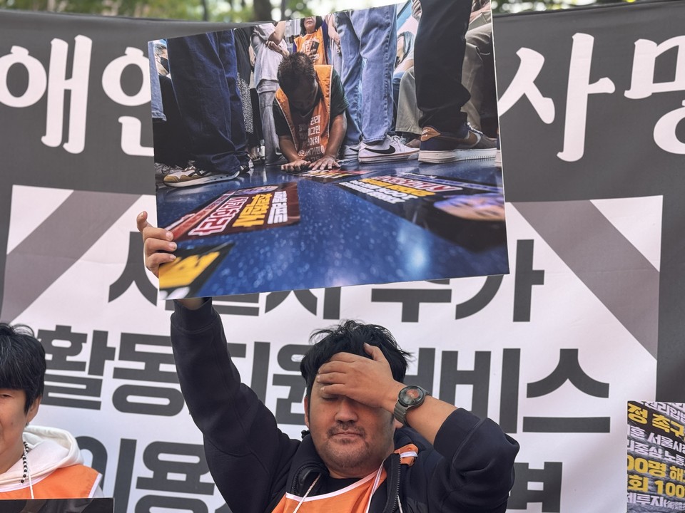 한 활동가가 포체투지하는 장애인의 사진을 들고 있다. 사진 전장연