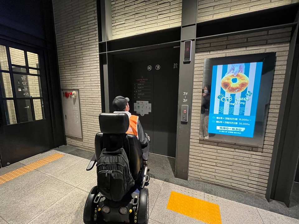 주재영 활동가가 용산역과 연결된 테이스트 파크 CGV 건물에서 4층으로 올라가는 엘리베이터 앞에 있다. 사진 전장연