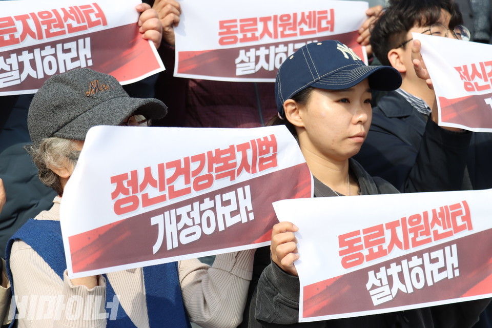 기자회견 참가자들이 작은 현수막을 들고 있다. 현수막에는 “정신건강복지법 개정하라!”, “동료지원센터 설치하라!”라고 적혀있다. 사진 김소영