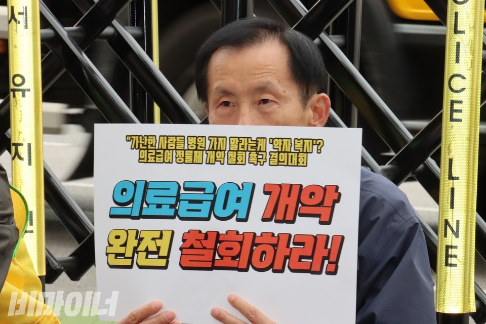 한 결의대회 참가자가 “의료급여 개악 완전 철회하라”라고 적힌 손팻말을 들고 있다. 사진 하민지