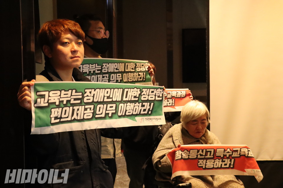 전국장애인야학협의회 활동가들이 방송통신고등학교 시도교육청 협의체 회의장에서 피케팅을 하고 있다. 작은 현수막에는 각각 “교육부는 장애인에 대한 정당한 편의제공 의무 이행하라!”(왼쪽), “방송통신고 특수교육과정 적용하라!”(오른쪽)라고 적혀있다. 사진 김소영