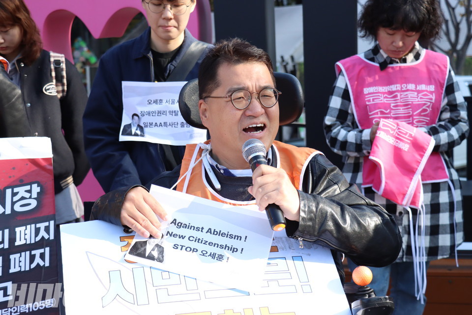 특사단원인 조재범 서울장애인차별철폐연대 활동가가 발언하고 있다. 그의 손에는 “Against Ableism!(비장애중심주의 철폐하라!) New Citizenship!(장애인도 시민으로 이동하는 시대로!) Stop 오세훈!(오세훈은 장애인권리 약탈을 멈춰라!)”라고 적힌 종이 피켓을 들고 있다. 사진 김소영
