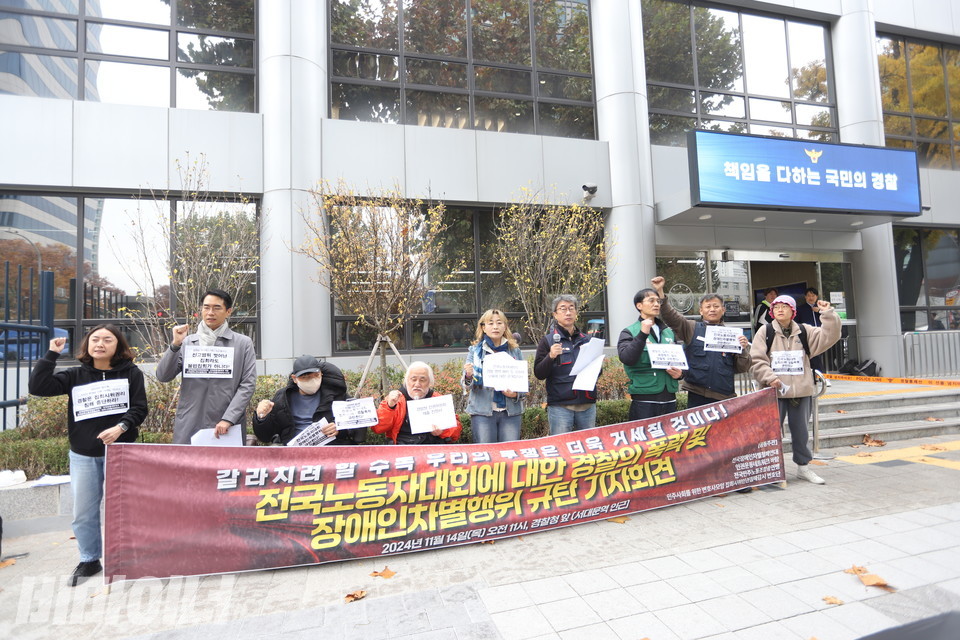 기자회견 참가자들이 구호를 외치고 있다. 참가자들 뒤에 있는 경찰청 건물의 전광판에는 “책임을 다하는 국민의 경찰”이라고 적혀있다. 사진 김소영