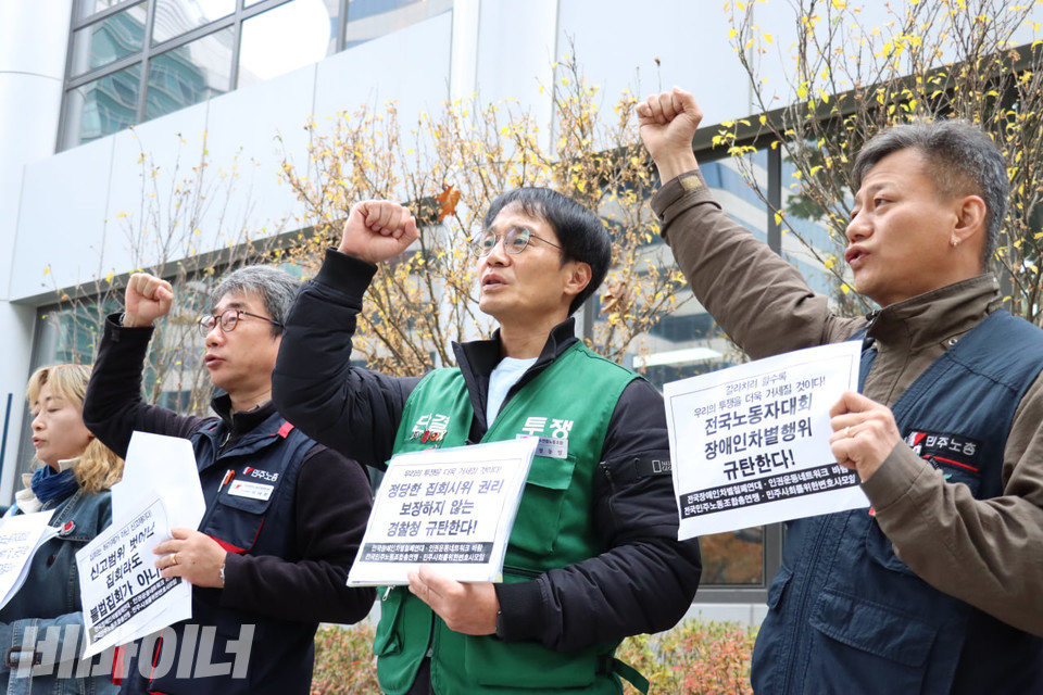 기자회견 참가자들이 주먹을 높이 들고 구호를 외치고 있다. 그들은 각자 “신고범위 벗어난 집회라도 불법집회가 아니다”(왼쪽), “정당한 집회시위 권리 보장하지 않는 경찰청 규탄한다!”(가운데), “전국노동자대회 장애인차별행위 규탄한다!”(오른쪽)라고 적힌 종이 피켓을 들고 있다. 사진 김소영