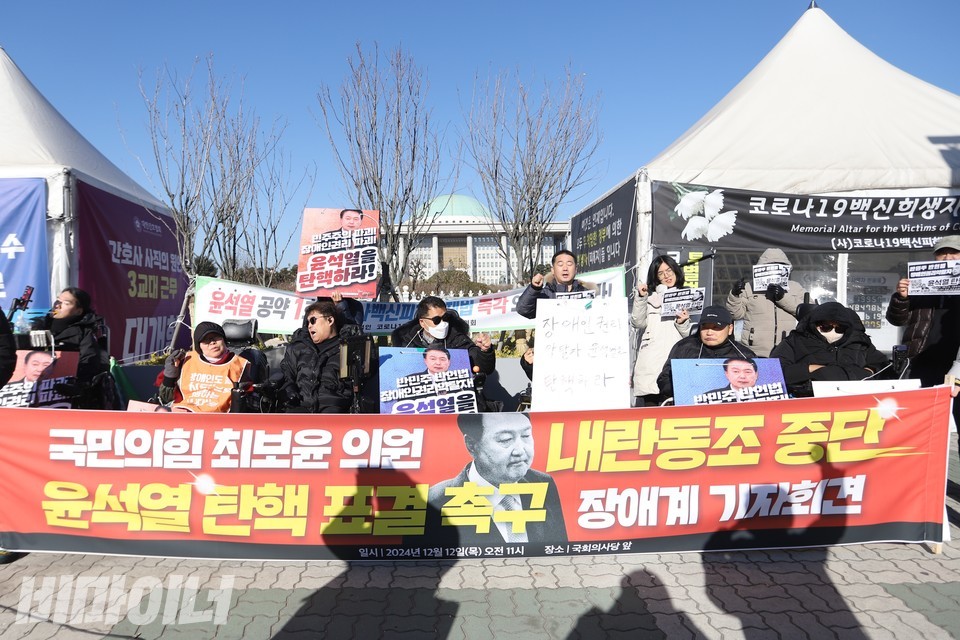 기자회견 참가자들이 구호를 외치고 있다. 기자회견 현장 뒤로는 국회의사당 본관이 보인다. 사진 김소영