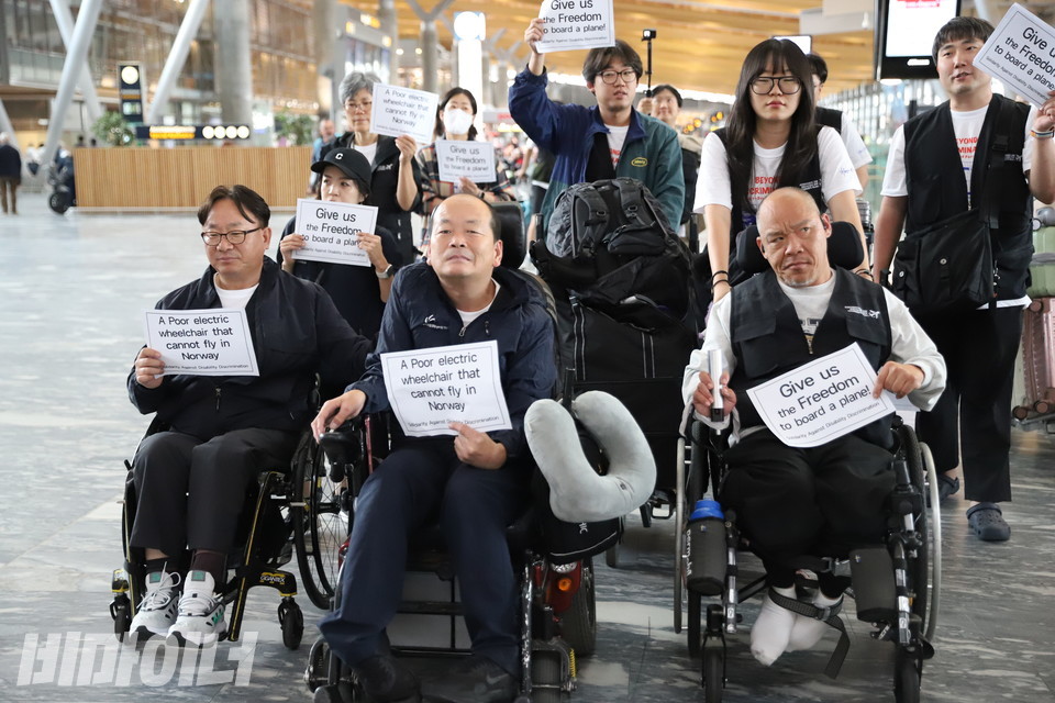 특사단이 노르웨이 오슬로 공항에 도착해 전동휠체어의 탑승을 거부한 항공사의 카운터로 항의를 하러 가고 있다. 특사단은 “우리에게 비행기를 탈 자유를 줘라”, “노르웨이에서 날 수 없는 불쌍한 전동 휠체어”라고 영어로 쓰여있는 종이 피켓을 들고 있다. 사진 김소영