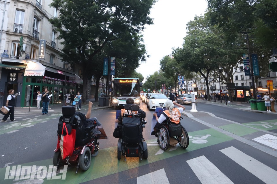 휠체어 이용 특사단원들이 프랑스 파리에서 도로를 막으며 구호를 외치고 있다. 사진 김소영