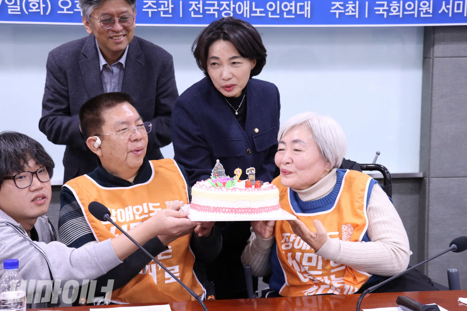 박명애 전장노련 대표와 권달주 전장연 상임공동대표, 서미화 의원이 함께 전장노련 창립 기념 케이크의 촛불을 불고 있다. 사진 김소영