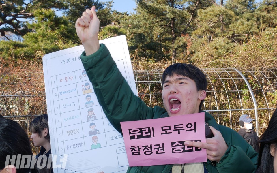 한 활동가가 발달장애인 공직선거 정보접근권 보장을 위한 차별구제소청구소송 승소를 기뻐하며 함성을 지르고 있다. 그는 “우리 모두의 참정권 승리”라는 피켓을 들고 있다. 사진 하민지