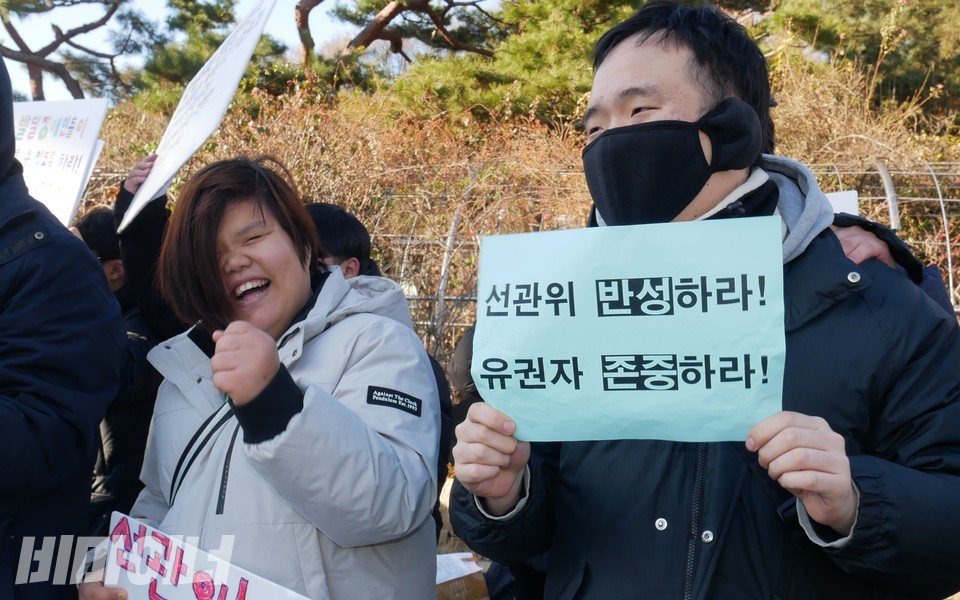 기자회견 참가자들이 웃고 있다. 한 참가자는 “선관위 반성하라, 유권자 존중하라”라고 적힌 피켓을 들고 있다. 사진 하민지