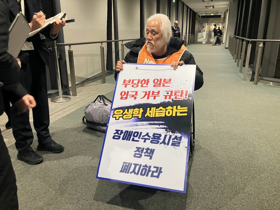 나리타공항에서 일본 입국을 거부당한 박경석 대표. 박 대표는 “부당한 일본 입국 거부 규탄! 우생학 세습하는 장애인수용시설 정책 폐지하라”라고 적힌 피켓을 들고 있다. 사진 전장연