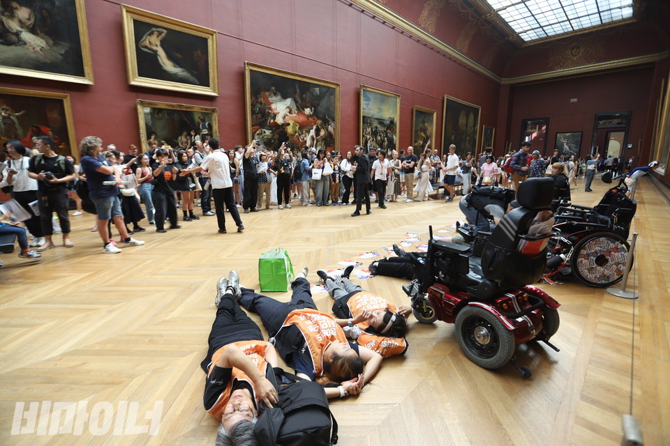 파리 패럴림픽 특사단이 루브르박물관에서 기습 ‘다이인 행동’을 벌이고 있다. 많은 관람객들이 특사단의 다이인 행동을 지켜보고 있다. 사진 김소영