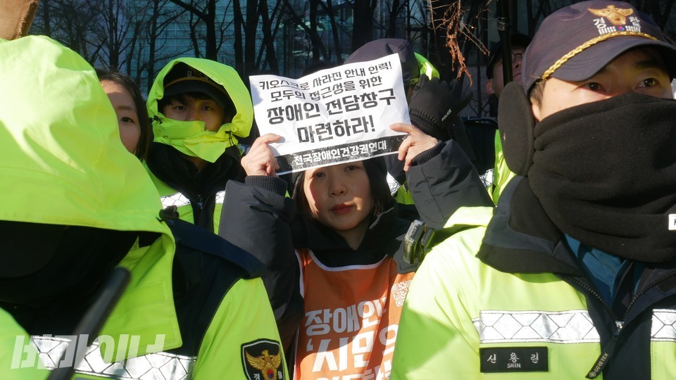 기자회견 참여자가 피켓을 들고 있다. 피켓에는 “키오스크로 사라진 안내 인력! 모두의 접근성을 위한 장애인 전담창구 마련하라!”라고 적혀 있다. 사진 하민지