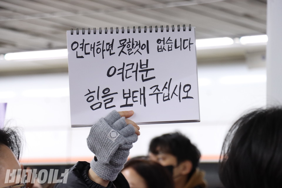 2일 오전, 서울 지하철 안국역에서 진행된 ‘출근길 지하철 다이인 행동’에 참여한 시민이 “연대하면 못 할 것이 없습니다. 여러분 힘을 보태주십시오”라고 적은 수첩을 높이 들고 있다. 사진 김소영