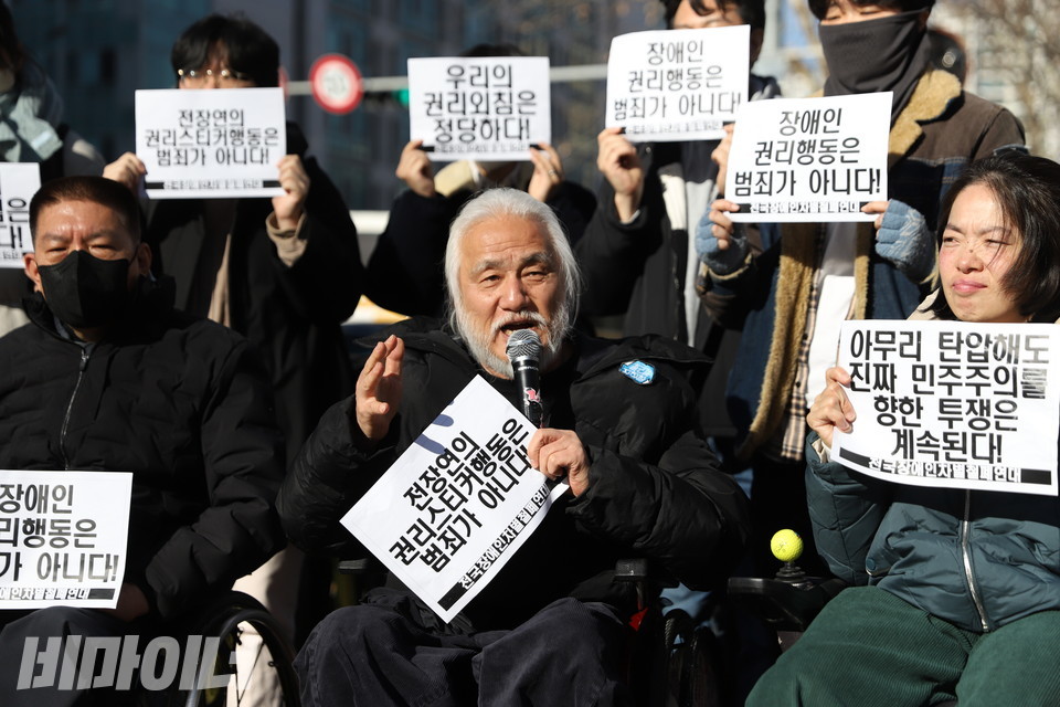 박경석 전장연 대표가 발언하고 있다. 그의 손에는 “전장연의 권리스티커 행동은 범죄가 아니다!”라고 적힌 종이 피켓이 들려있다. 사진 김소영 