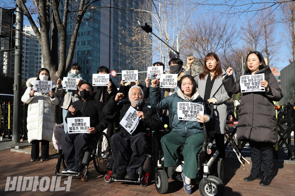 23일, 전국장애인차별철폐연대가 지하철 승강장에 장애인의 권리를 알리는 ‘권리스티커를 부착했다’는 이유로 유죄를 선고받은 뒤 입장 발표를 하고 있다. 활동가들과 변호사들이 주먹을 쥐며 구호를 외치고 있다. 사진 김소영