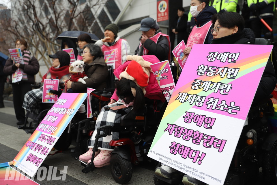 장애인 당사자들이 기자회견에 참가하고 있다. 한 참가자는 “장애인활동지원중개기관 재지정 취소는 장애인 자립생활권리 침해다!”라고 적힌 피켓을 들고 있다. 사진 김소영