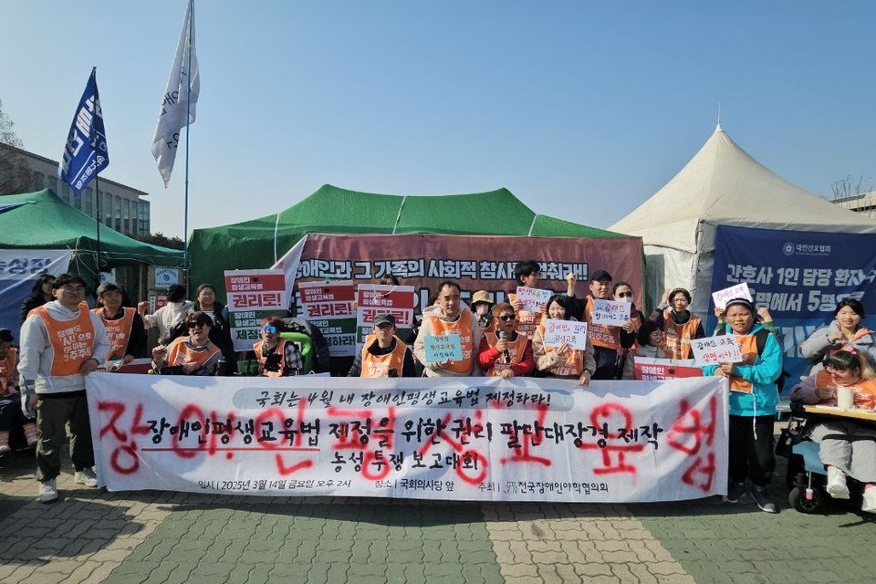 14일 오후, 보고대회 참여자들이 빨간 라카로 “장애인평생교육법”이라고 직접 적은 ‘장애인평생교육법 제정을 위한 권리 팔만대장경 제작 농성 투쟁 보고대회’의 흰색 현수막을 들고 있다. 사진 전장야협 제공