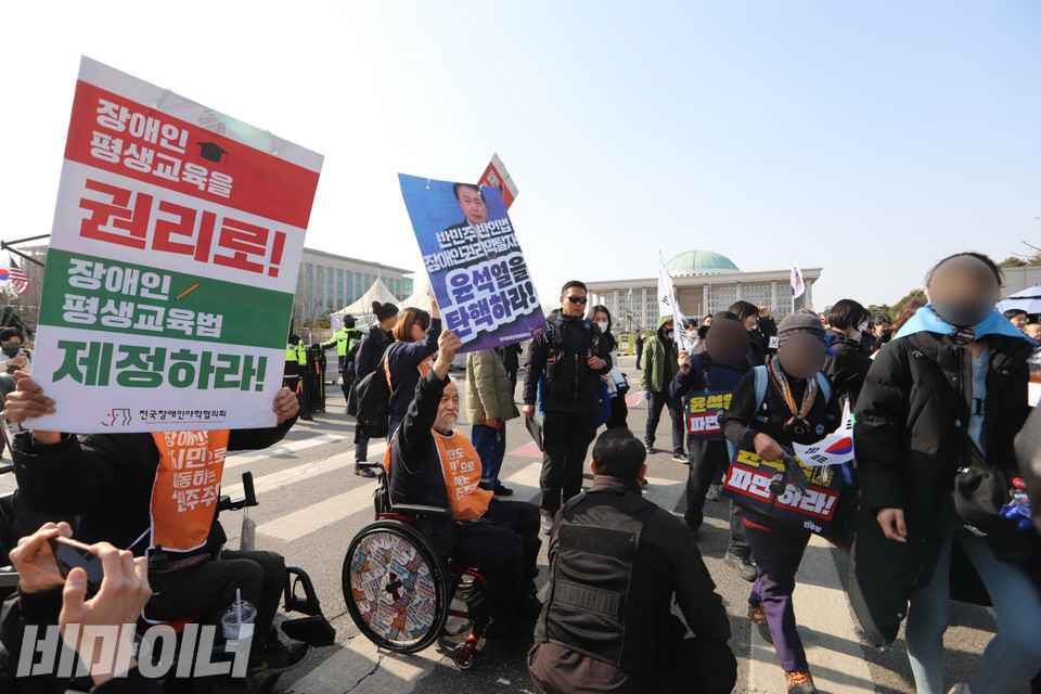 전장야협 활동가들이 피켓을 높이 들며 도보행진을 하는 더불어민주당 국회의원 및 더불어민주당 지지자들에게 장애인평생교육법 제정의 필요성을 외치고 있다. 사진 김소영