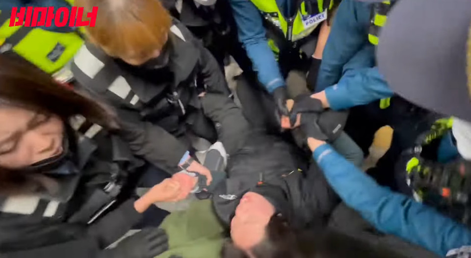 서울교통공사 보안관들과 경찰들이 문애린 활동가를 휠체어에서 분리시킨 뒤 문 활동가의 사지를 들고 옮기고 있다. 사진 비마이너 영상 캡처