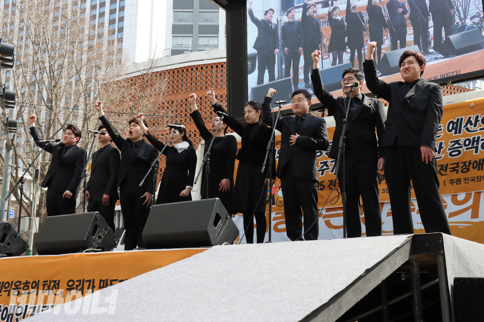 발달장애인 중창단 광진 미라클보이스앙상블이 공연하고 있다. 무대에 오른 이들은 주먹을 쥔 손을 높이 들며 노래를 부르고 있다. 사진 김소영