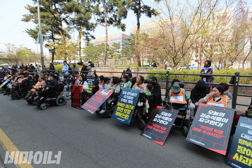 기자회견에 참여한 장애인들의 모습. “오늘의 김순석들이 요구한다! 거리의 턱을 없애 주십시오!”, “6차 편의증진 국가종합 5개년 계획, 장애인 접근권 완전 보장 계획으로!” 등이 쓰인 피켓을 목에 걸고 있다. 사진 김소영