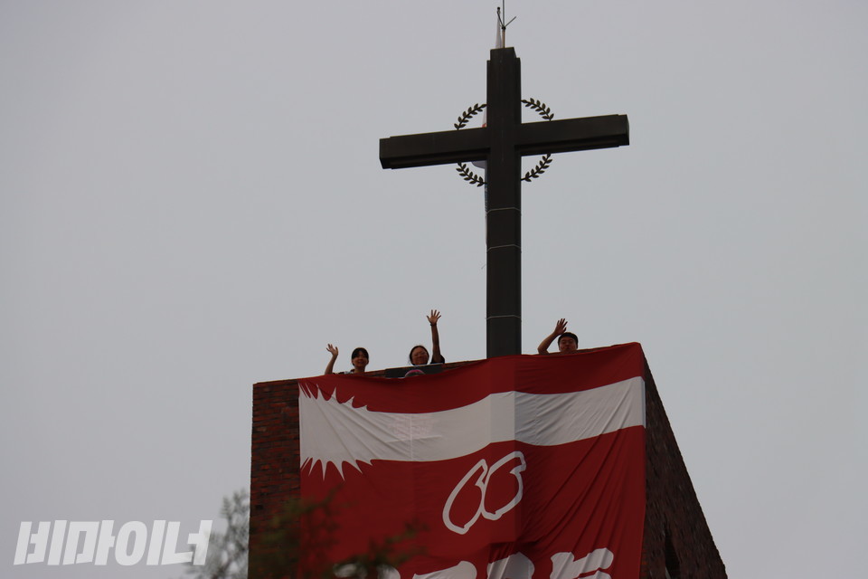 종탑 위에 올라 성당 아래에 있는 시민들에게 인사하고 있는 활동가들. 왼쪽부터 박초현 활동가, 민푸름 활동가, 이학인 활동가. 사진 김소영