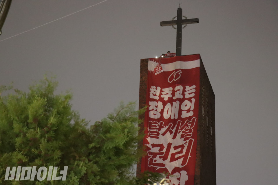 성당 종탑 위에 있는 활동가들이 플래시를 키며 연대시민들에게 화답하고 있다. 사진 김소영