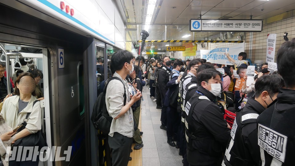 혜화역 승강장. 열차 문이 열려 있다. 장애인들은 타지 못 한 채 서울교통공사 직원들에 가로막혀 있다. 사진 하민지