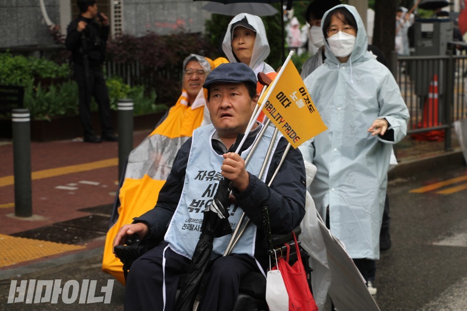 탈시설장애인 김진석 씨가 장애인노동권 깃발을 흔들며 행진하고 있다. 사진 하민지