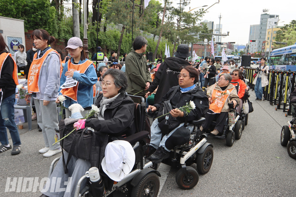 헌화하기 위해 줄지어 있는 휠체어 이용 장애인들. 그들의 손에는 국화꽃이 들려 있다. 사진 김소영