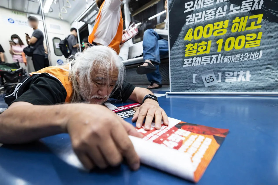 박경석 전장연 대표가 휠체어 아래로 내려와 출근길 지하철 바닥을 기며 장애인권리 스티커를 붙이는 ‘포체투지’(匍體投地)를 하고 있다. 사진 전장연 제공