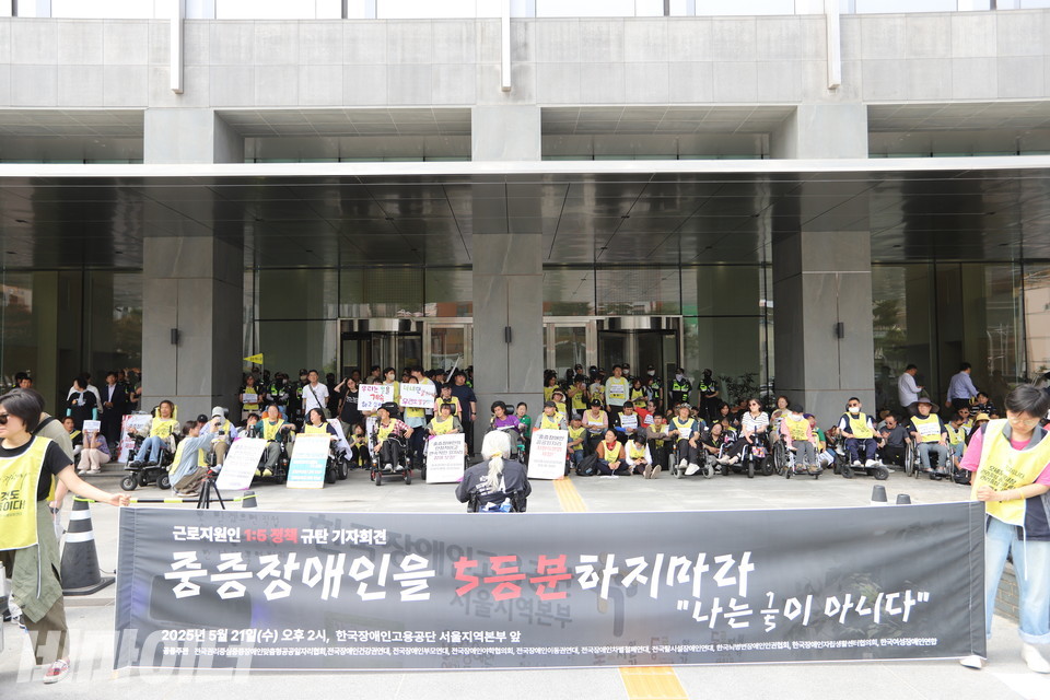 전권협 등 장애계가 21일 오후 2시 한국장애인고용공단 서울지역본부 앞에서 기자회견을 열고 있다. 100여 명의 참여자들이 건물 문 앞을 가득 메우고 있다. 그들의 앞에는 “중증장애인을 5등분하지 말라. 나는 1/5이 아니다”라고 적힌 플래카드가 있다. 사진 김소영