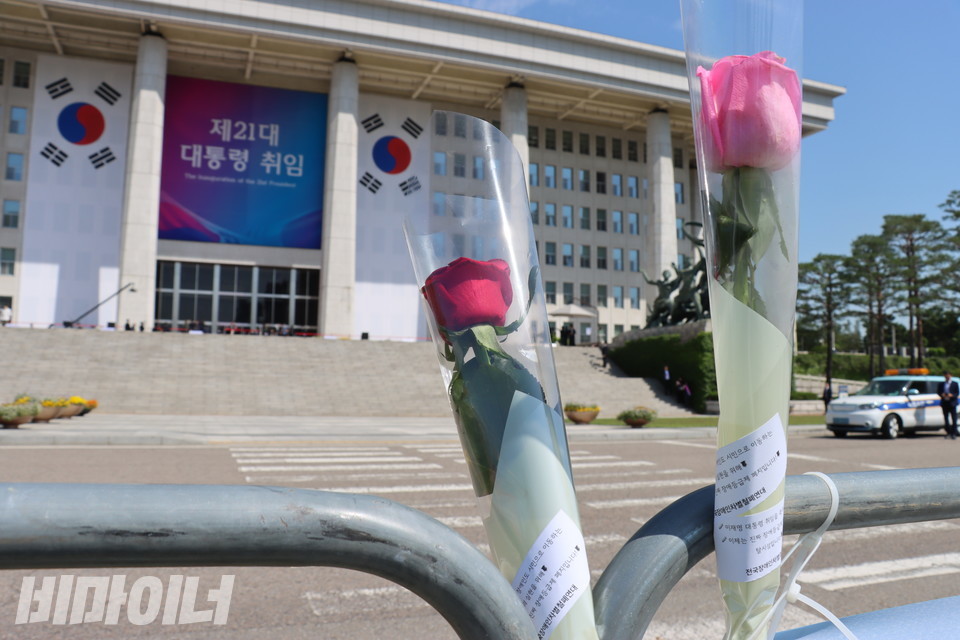 바리케이드에 꽂힌 장미꽃들. 그 뒤로 “제21대 대통령 취임”이라고 적힌 천막이 걸린 국회 본관이 보인다. 사진 김소영