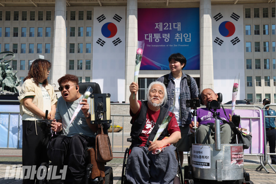 장애인들이 경찰의 저지에도 국회 본관 앞까지 갔지만, 바리케이드가 설치돼 있어 취임식장에 들어서지 못했다. 오영철·박경석 전장연 상임공동대표와 이규식 서울장애인차별철폐연대 상임대표(왼쪽부터)가 꽃을 들고 있다. 사진 김소영